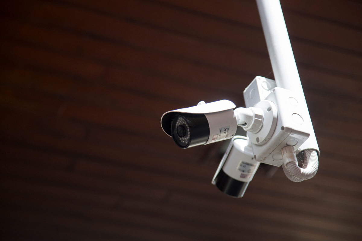 Three CCTV surveillance cameras mounted on a security pole monitoring the surrounding area.