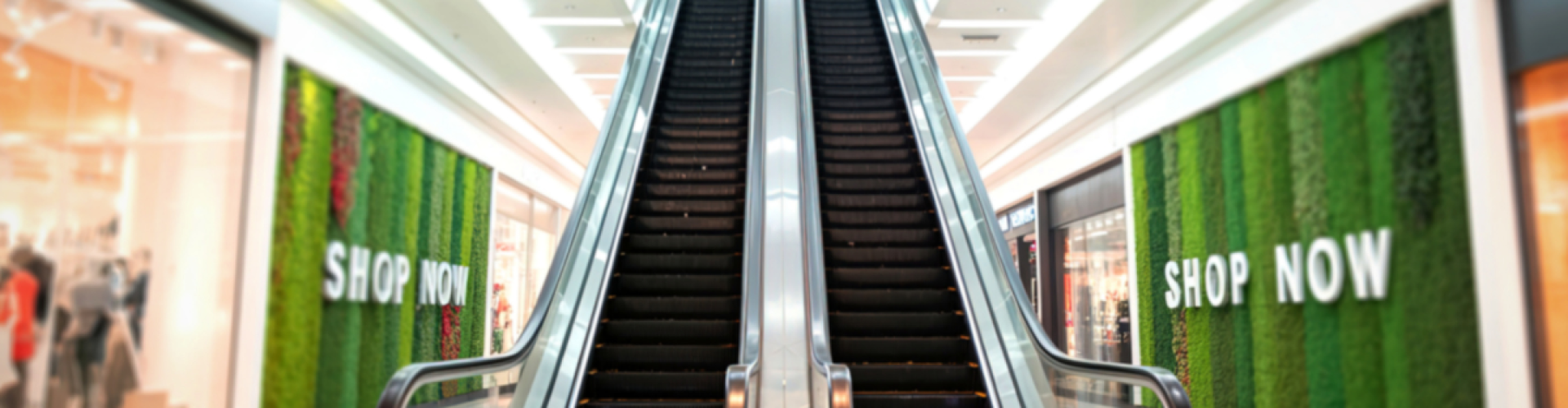 Escalator inside a shopping mall with a promotional sign encouraging shopping while highlighting business and inventory protection.